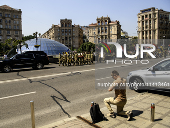 A man is kneeling as the funeral procession for Mykola Kokhanivskyi, commander of the OUN (Organisation of Ukrainian Nationalists) volunteer...