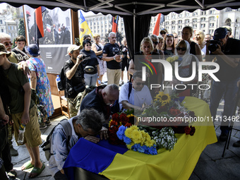 People are kneeling at the coffin of Mykola Kokhanivskyi, commander of the OUN (Organisation of Ukrainian Nationalists) volunteer battalion,...