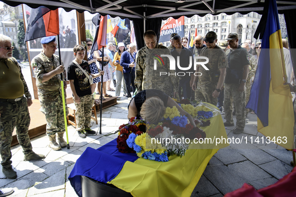 A woman is kneeling at the coffin of Mykola Kokhanivskyi, commander of the OUN (Organisation of Ukrainian Nationalists) volunteer battalion,...