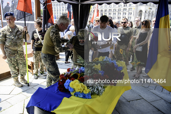 A man is kneeling at the coffin of Mykola Kokhanivskyi, commander of the OUN (Organisation of Ukrainian Nationalists) volunteer battalion, d...