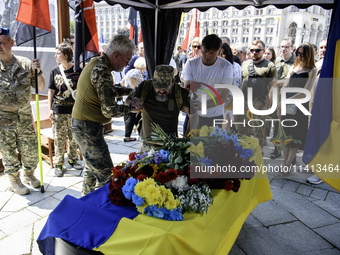 A man is kneeling at the coffin of Mykola Kokhanivskyi, commander of the OUN (Organisation of Ukrainian Nationalists) volunteer battalion, d...