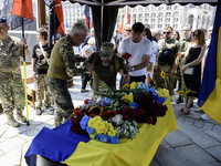 A man is kneeling at the coffin of Mykola Kokhanivskyi, commander of the OUN (Organisation of Ukrainian Nationalists) volunteer battalion, d...