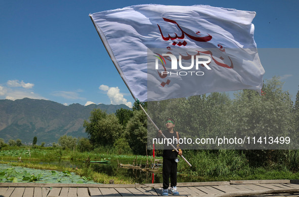 A Kashmiri Shiite Muslim child is waving a religious flag during a Muharram procession on the ninth day of Ashura in the interiors of Dal La...