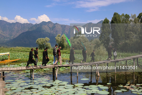 Kashmiri Shiite Muslim mourners are walking across a wooden footbridge as they are participating in a Muharram procession on the ninth day o...