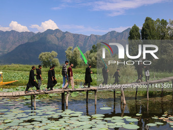 Kashmiri Shiite Muslim mourners are walking across a wooden footbridge as they are participating in a Muharram procession on the ninth day o...