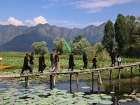 Kashmiri Shiite Muslim mourners are walking across a wooden footbridge as they are participating in a Muharram procession on the ninth day o...