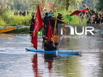 A Kashmiri Shiite, along with his kids, is rowing his kayak as they are taking part in a Muharram procession on the ninth day of Ashura in t...