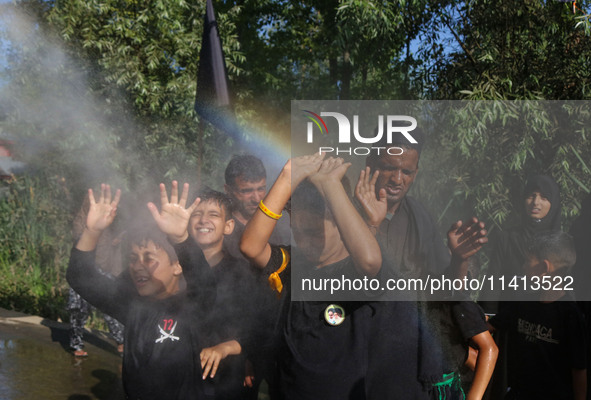 Kashmiri Shiite Muslim mourners are receiving a cold water spray during a Muharram procession on the ninth day of Ashura in the interiors of...