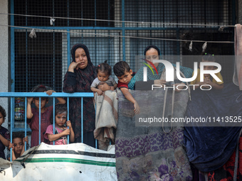 Palestinians are looking at a UN school sheltering displaced people, following an Israeli strike, amid the Israel-Hamas conflict, in Nuseira...