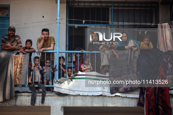 Palestinians are looking at a UN school sheltering displaced people, following an Israeli strike, amid the Israel-Hamas conflict, in Nuseira...