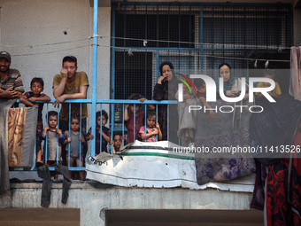 Palestinians are looking at a UN school sheltering displaced people, following an Israeli strike, amid the Israel-Hamas conflict, in Nuseira...