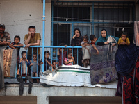 Palestinians are looking at a UN school sheltering displaced people, following an Israeli strike, amid the Israel-Hamas conflict, in Nuseira...