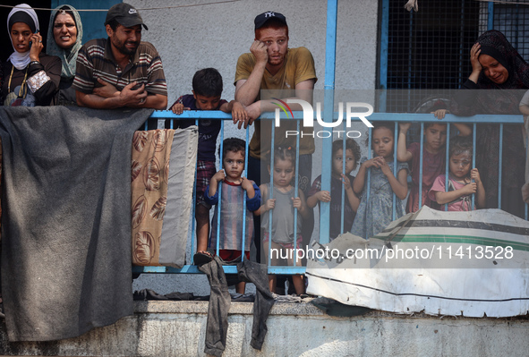 Palestinians are looking at a UN school sheltering displaced people, following an Israeli strike, amid the Israel-Hamas conflict, in Nuseira...