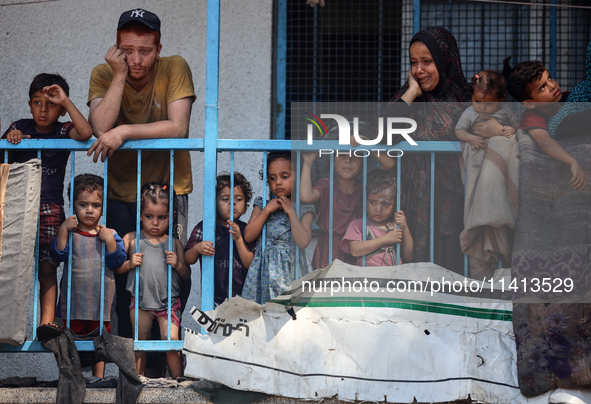 Palestinians are looking at a UN school sheltering displaced people, following an Israeli strike, amid the Israel-Hamas conflict, in Nuseira...