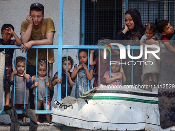 Palestinians are looking at a UN school sheltering displaced people, following an Israeli strike, amid the Israel-Hamas conflict, in Nuseira...