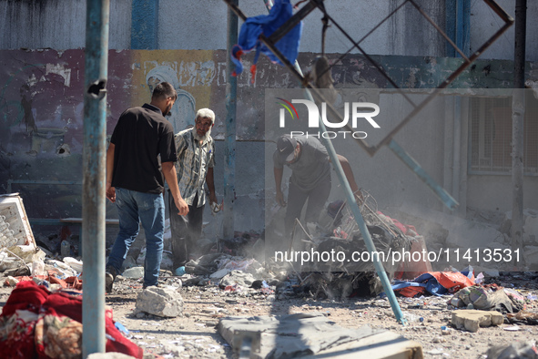 Palestinians are inspecting a UN school sheltering displaced people, following an Israeli strike, amid the Israel-Hamas conflict, in Nuseira...