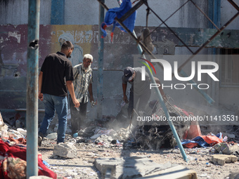 Palestinians are inspecting a UN school sheltering displaced people, following an Israeli strike, amid the Israel-Hamas conflict, in Nuseira...