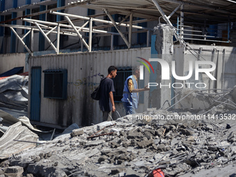 Palestinians are inspecting a UN school sheltering displaced people, following an Israeli strike, amid the Israel-Hamas conflict, in Nuseira...