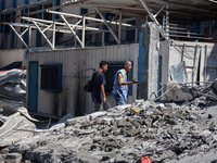 Palestinians are inspecting a UN school sheltering displaced people, following an Israeli strike, amid the Israel-Hamas conflict, in Nuseira...