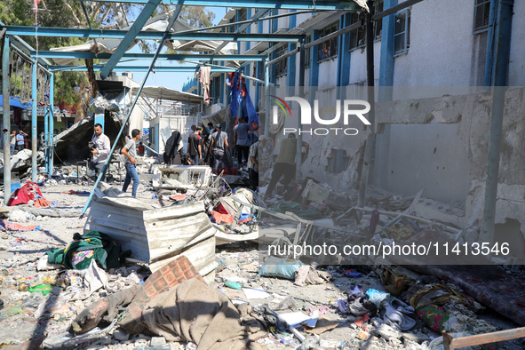 Palestinians are inspecting a UN school sheltering displaced people, following an Israeli strike, amid the Israel-Hamas conflict, in Nuseira...