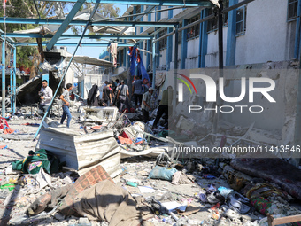 Palestinians are inspecting a UN school sheltering displaced people, following an Israeli strike, amid the Israel-Hamas conflict, in Nuseira...