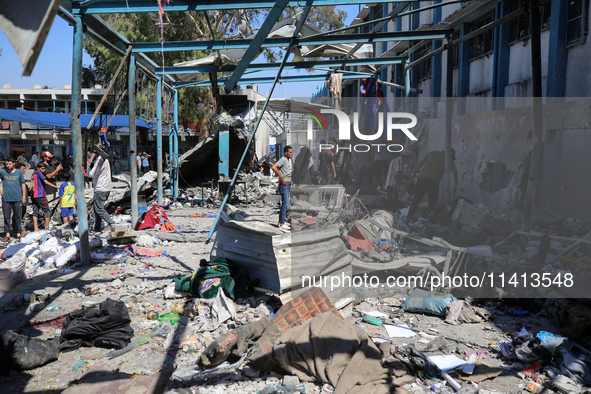 Palestinians are inspecting a UN school sheltering displaced people, following an Israeli strike, amid the Israel-Hamas conflict, in Nuseira...