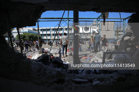 Palestinians are inspecting a UN school sheltering displaced people, following an Israeli strike, amid the Israel-Hamas conflict, in Nuseira...