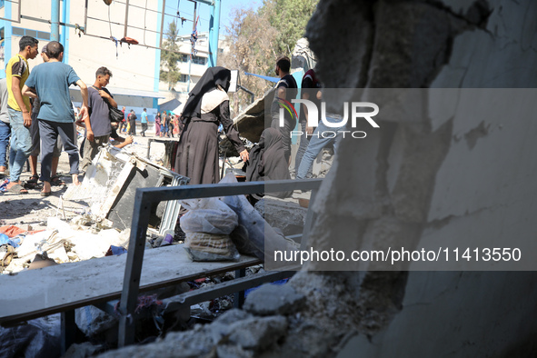 Palestinians are inspecting a UN school sheltering displaced people, following an Israeli strike, amid the Israel-Hamas conflict, in Nuseira...