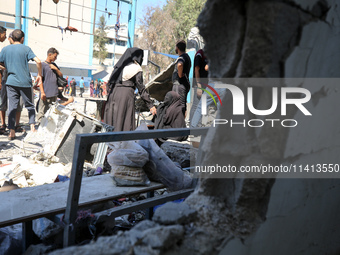 Palestinians are inspecting a UN school sheltering displaced people, following an Israeli strike, amid the Israel-Hamas conflict, in Nuseira...