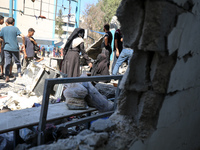 Palestinians are inspecting a UN school sheltering displaced people, following an Israeli strike, amid the Israel-Hamas conflict, in Nuseira...