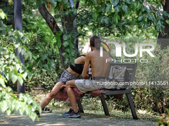 A man and woman are sitting on the bench in the shadow on a hot summer day in Odesa, Ukraine, on July 13, 2024. NO USE RUSSIA. NO USE BELARU...