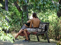 A man and woman are sitting on the bench in the shadow on a hot summer day in Odesa, Ukraine, on July 13, 2024. NO USE RUSSIA. NO USE BELARU...