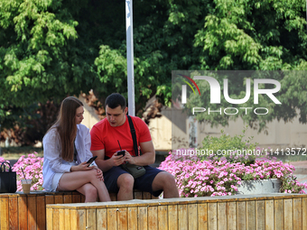 A man and woman are talking while sitting on the bench in the shadow in Odesa, Ukraine, on July 13, 2024. NO USE RUSSIA. NO USE BELARUS. (