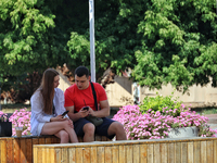 A man and woman are talking while sitting on the bench in the shadow in Odesa, Ukraine, on July 13, 2024. NO USE RUSSIA. NO USE BELARUS. (