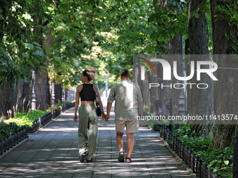 A man and woman are walking hand in hand along an alley on a hot summer day in Odesa, Ukraine, on July 13, 2024. NO USE RUSSIA. NO USE BELAR...