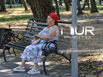 An elderly woman is sitting on the bench in the shadow in Odesa, Ukraine, on July 13, 2024. (