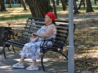 An elderly woman is sitting on the bench in the shadow in Odesa, Ukraine, on July 13, 2024. (