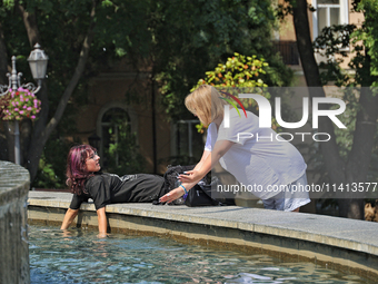 Two women are cooling their hands in a fountain on a hot summer day in Odesa, Ukraine, on July 13, 2024. NO USE RUSSIA. NO USE BELARUS. (