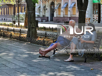 An elderly man and woman are sitting on the bench in the shadow on a hot summer day in Odesa, Ukraine, on July 13, 2024. NO USE RUSSIA. NO U...