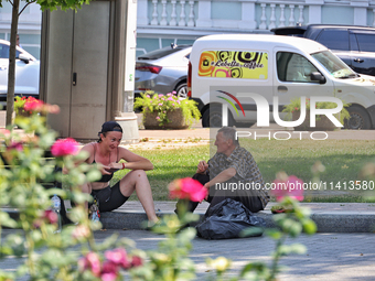 A man and woman are sitting on the curb on a hot summer day in Odesa, Ukraine, on July 13, 2024. NO USE RUSSIA. NO USE BELARUS. (