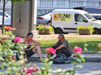 A man and woman are sitting on the curb on a hot summer day in Odesa, Ukraine, on July 13, 2024. NO USE RUSSIA. NO USE BELARUS. (