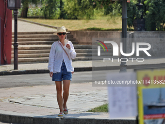 A woman in a hat and sunglasses is drinking a beverage on a hot summer day in Odesa, Ukraine, on July 13, 2024. NO USE RUSSIA. NO USE BELARU...