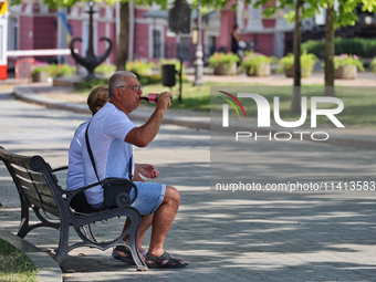 An elderly man is having a soft drink on the bench in the shadow on a hot summer day in Odesa, Ukraine, on July 13, 2024. NO USE RUSSIA. NO...