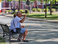 An elderly man is having a soft drink on the bench in the shadow on a hot summer day in Odesa, Ukraine, on July 13, 2024. NO USE RUSSIA. NO...