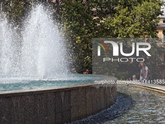 A woman and children are standing by a fountain on a hot summer day in Odesa, Ukraine, on July 13, 2024. NO USE RUSSIA. NO USE BELARUS. (