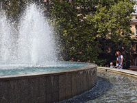 A woman and children are standing by a fountain on a hot summer day in Odesa, Ukraine, on July 13, 2024. NO USE RUSSIA. NO USE BELARUS. (