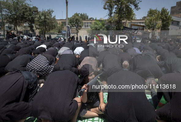 A young boy is holding a flag while Iraqi men living in Iran are praying during a religious festival to commemorate Ashura, in Dolatabad nei...