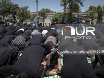 A young boy is holding a flag while Iraqi men living in Iran are praying during a religious festival to commemorate Ashura, in Dolatabad nei...