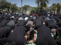 A young boy is holding a flag while Iraqi men living in Iran are praying during a religious festival to commemorate Ashura, in Dolatabad nei...