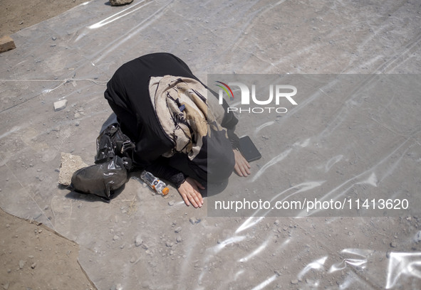 An Iraqi woman living in Iran is praying during a religious festival to commemorate Ashura in the Dolatabad neighborhood in southern Tehran,...